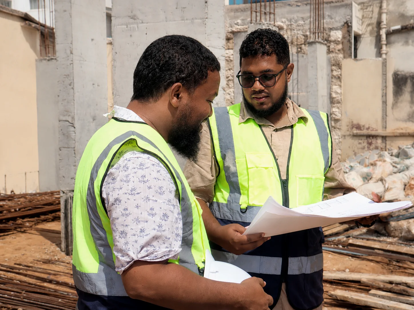 Engineers reviewing construction drawings together on site