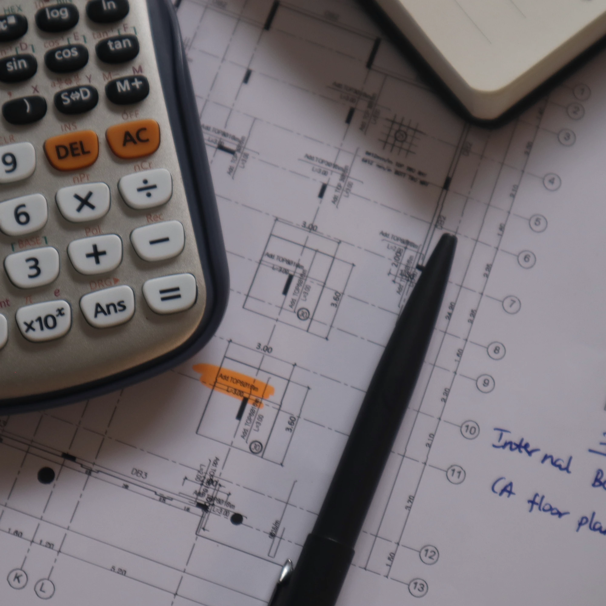 Engineering workspace with structural drawings, calculator, and pen